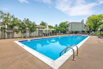 A large outdoor swimming pool with a metal ladder on the side. at Windsor Crest Apartments, Davenport  52807